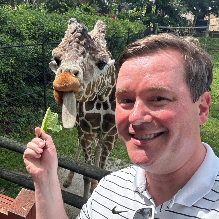 Photo of Paul Thelen with Jacoby--an adult giraffe at the Blank Park Zoo in Des Moines.